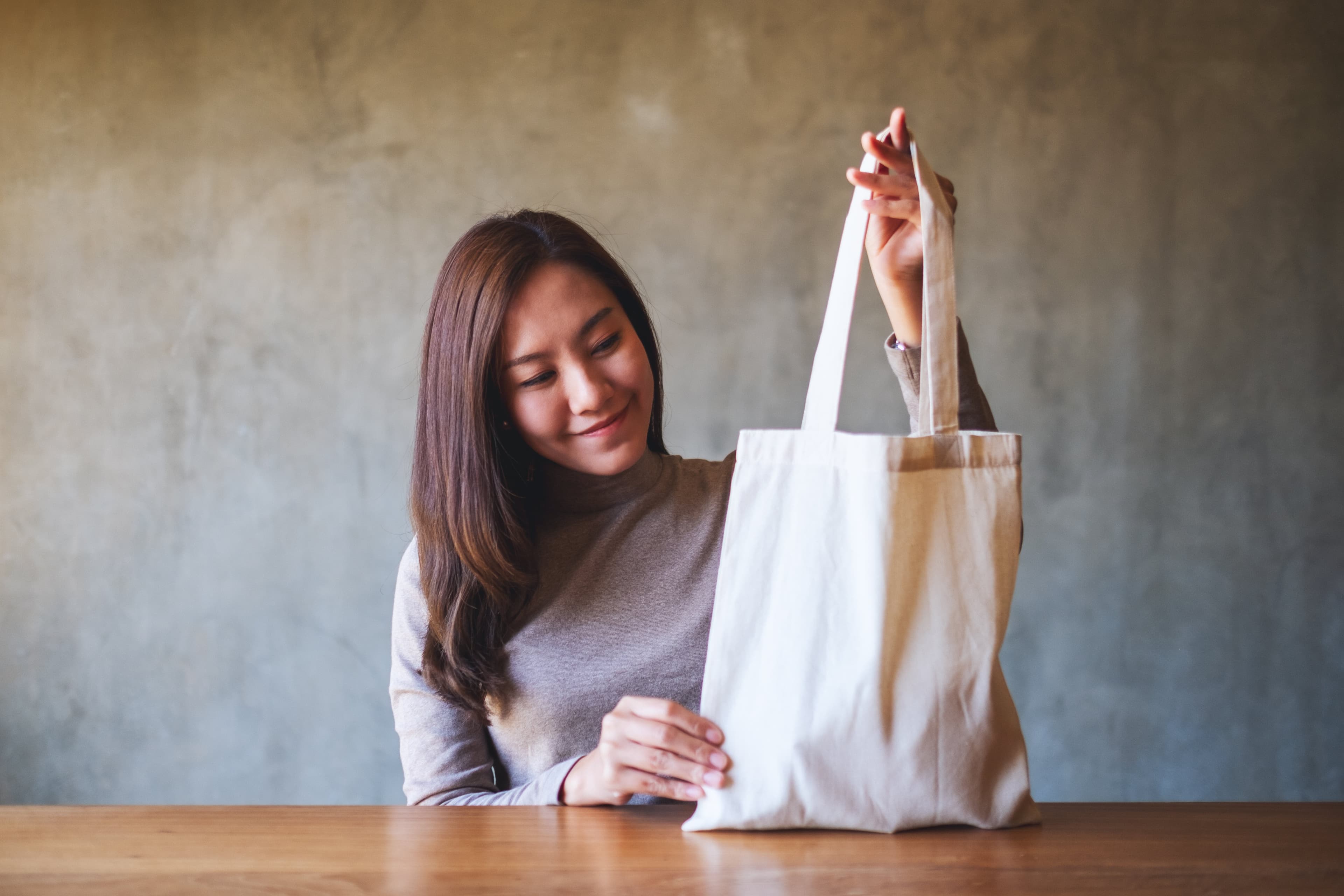 a woman holding and carrying a white fabric tote b 2022 10 06 22
