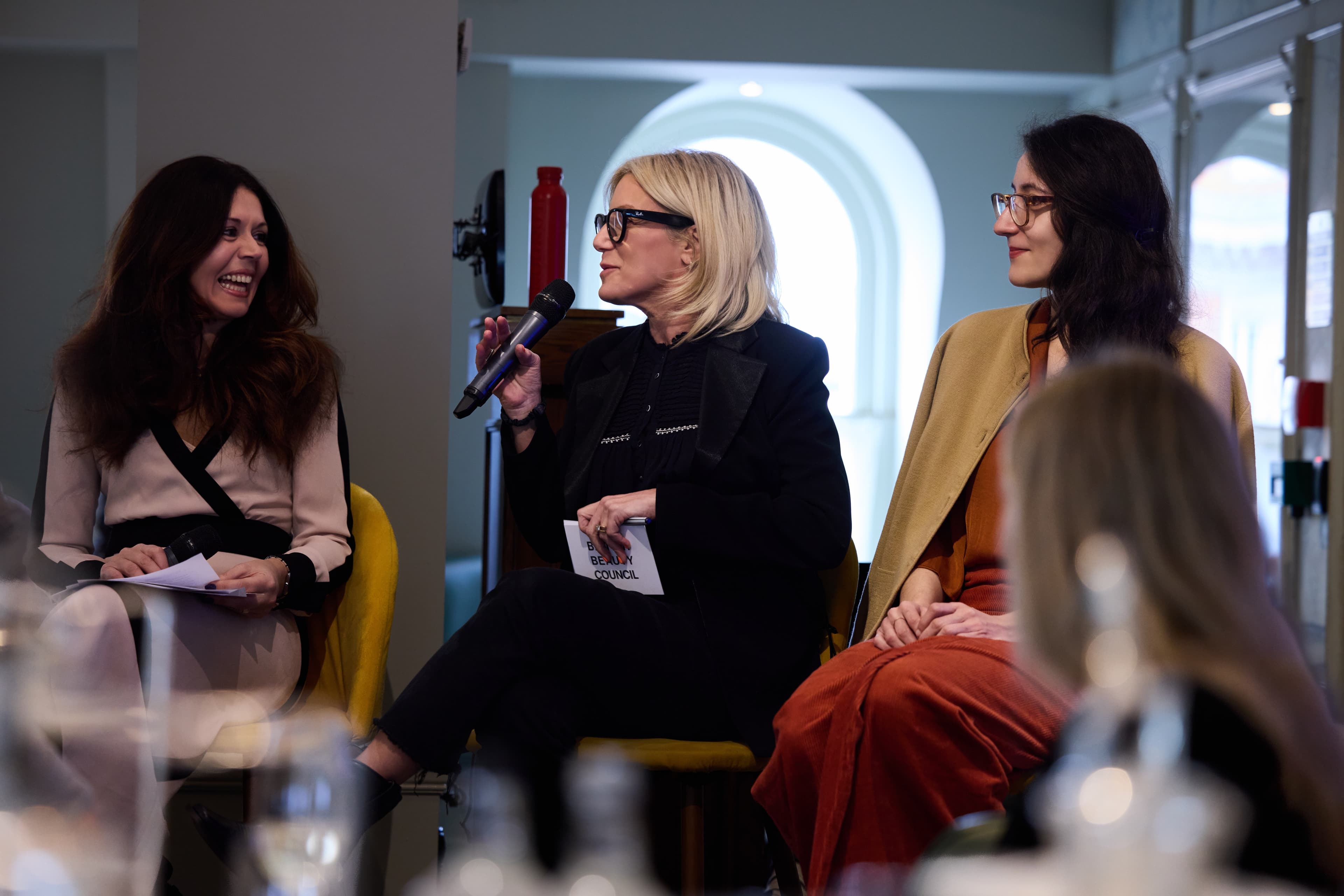 Panelists on stage at Revieve's beauty industry event in London, one speaking into a microphone