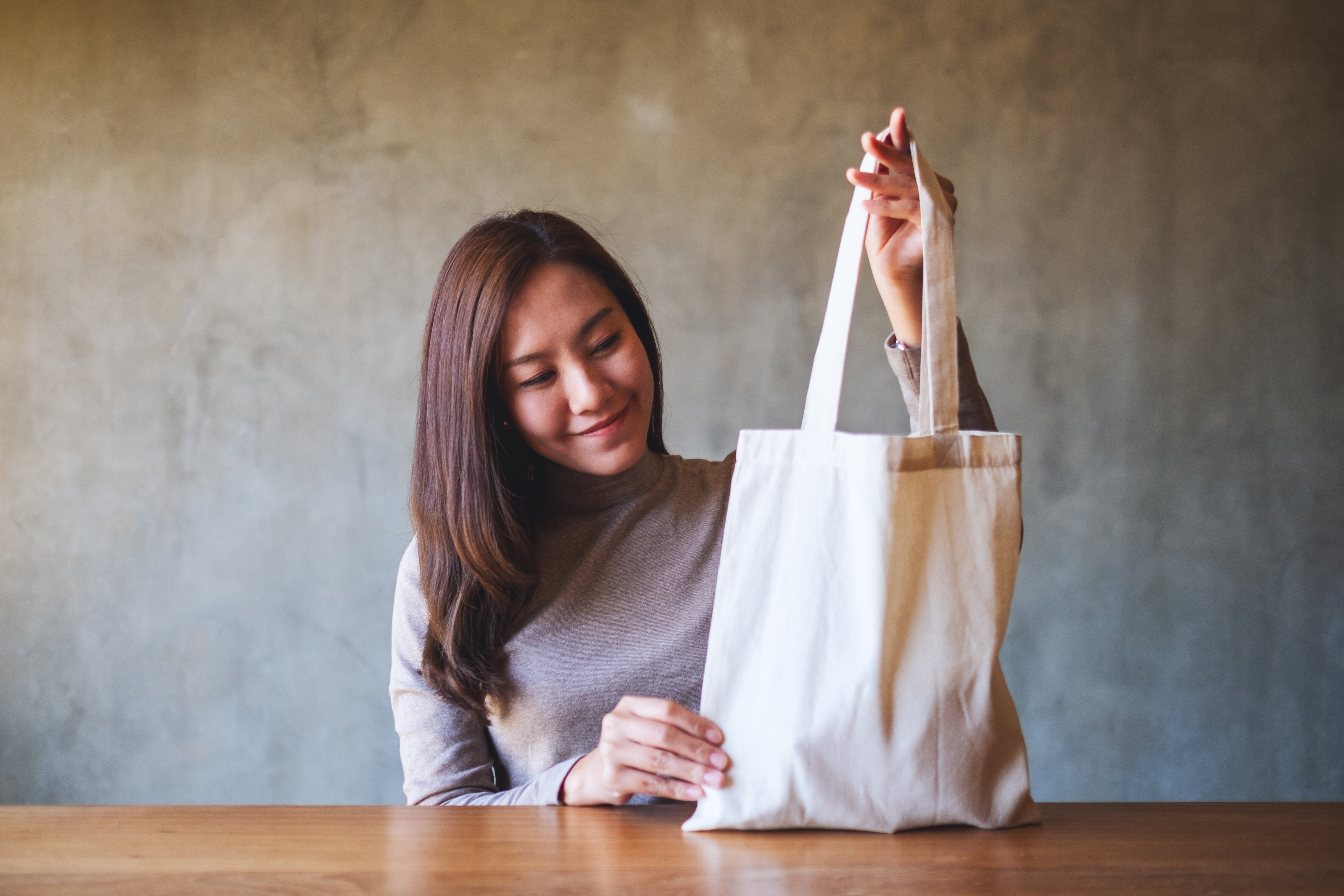 a woman holding and carrying a white fabric tote b 2022 10 06 22